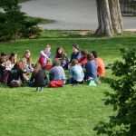 A group of adults sitting in a circle on the grass, talking