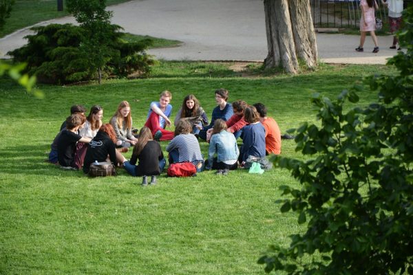A group of adults sitting in a circle on the grass, talking
