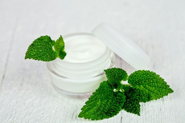 An open jar of skin cream on a white table