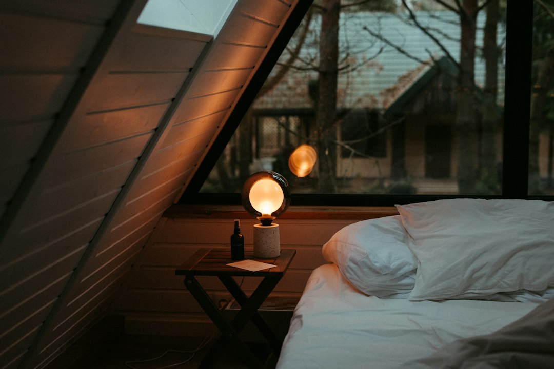 A tidy bed under a window beside a night stand