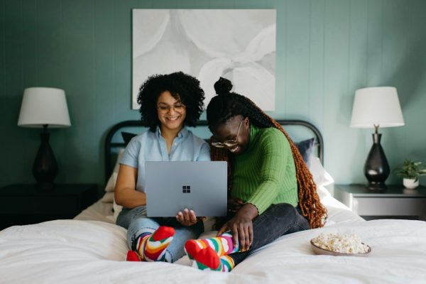 A woman sitting on a bed browsing on a laptop