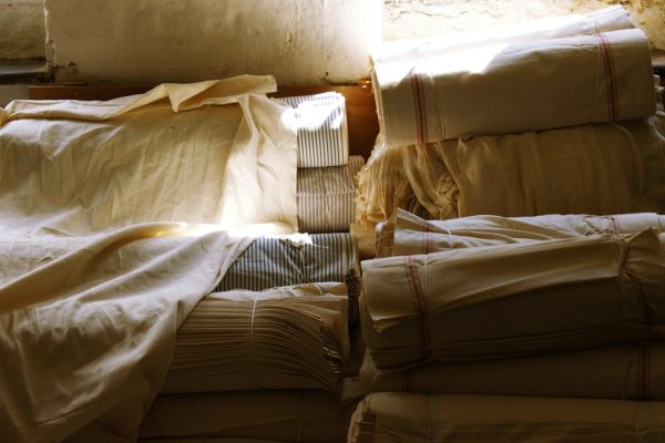 A pile of cotton and linen textiles in warm window light