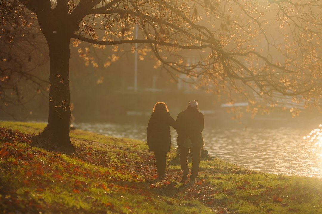 An adult couple walking beside a river at sunset