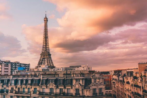 The Eiffel Tower rising over Paris rooftops at a pink sunset