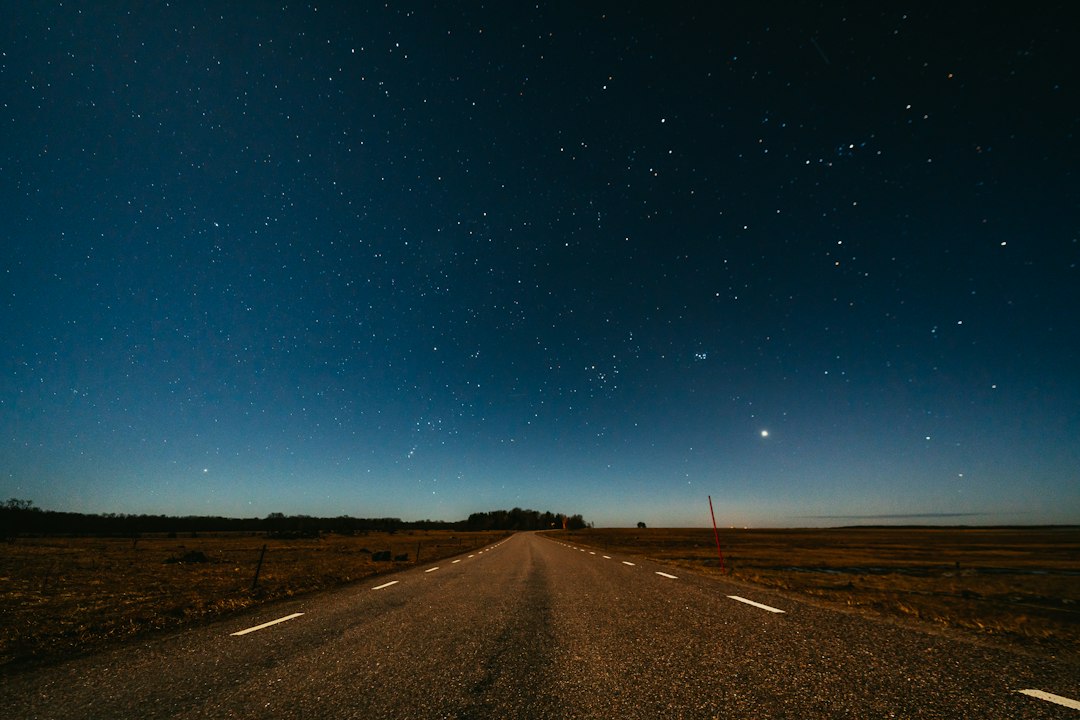 A long, empty road stretching toward the horizon under a sky full of stars