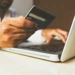 A person holding a credit card while shopping online on a laptop
