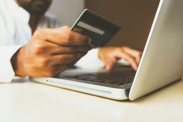 A person holding a credit card while shopping online on a laptop